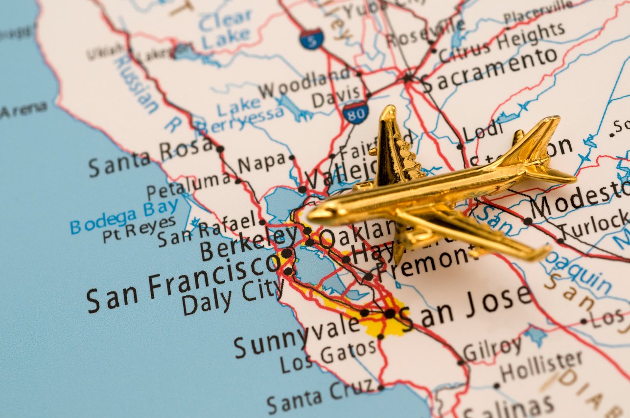 Small gold airplane toy landing in a map at San Francisco